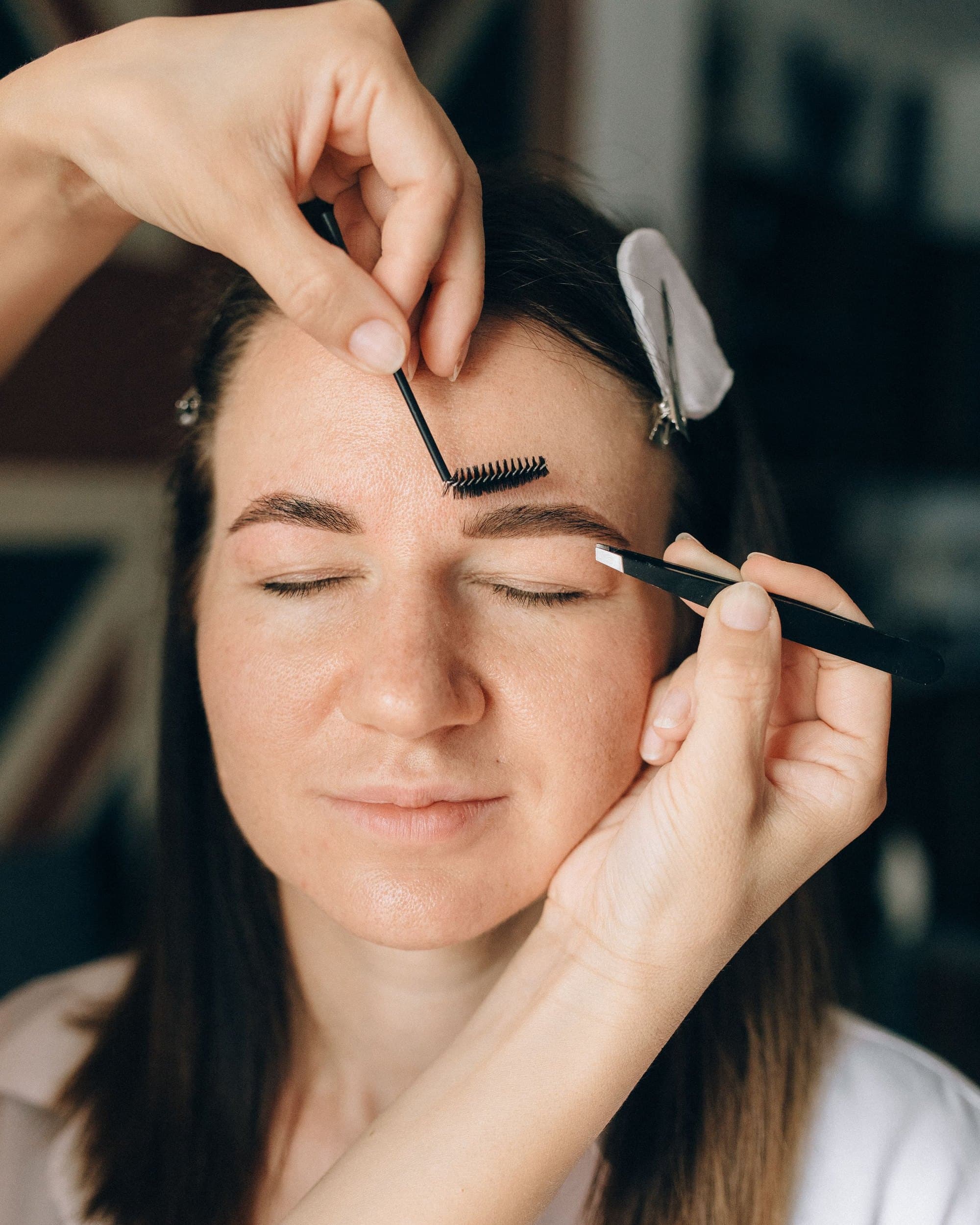 A brow artist brushing a client's eyebrows into shape