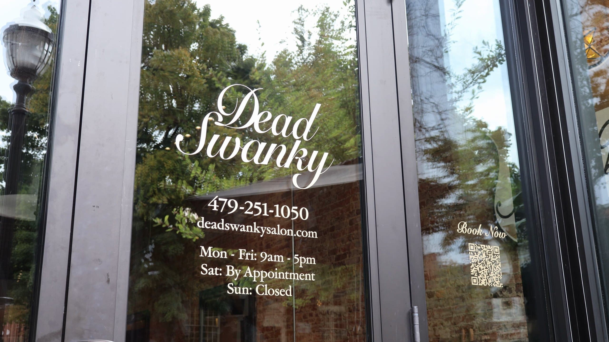 The salon's front door: Dead Swanky in white script on the glass, with the phone number and opening hours beneath